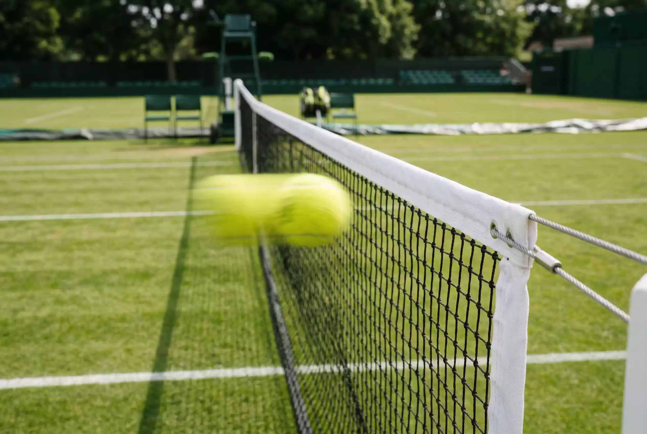 Pelota de tenis pasando a alta velocidad junto a red de césped
